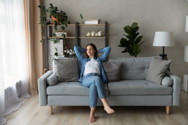 Happy young woman relaxing on comfortable sofa.