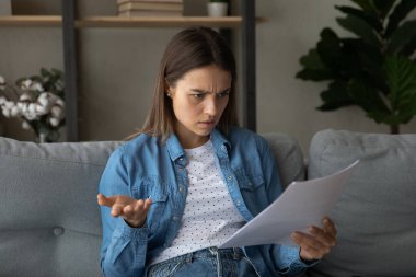 Unhappy young woman feeling anxious reading news.