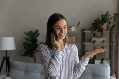 Joyful millennial woman holding distant phone call conversation.