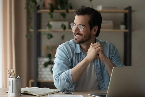 Uśmiechnięty młodzieniec w okularach rozkojarzony z pracą komputera. — Zdjęcie stockowe