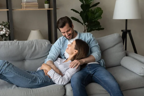 Happy bonding young family couple resting on comfortable sofa. — Stok fotoğraf