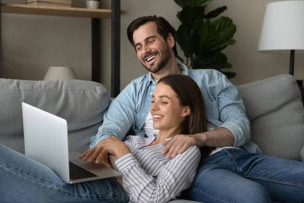 Joyful loving young family couple watching funny movie on computer. — Stockfoto