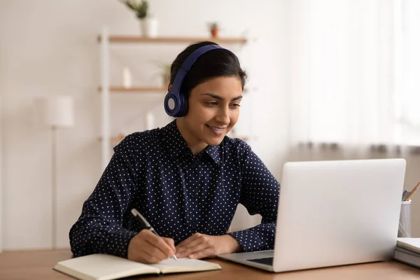 Счастливая молодая женщина в наушниках учиться онлайн на ноутбуке — стоковое фото