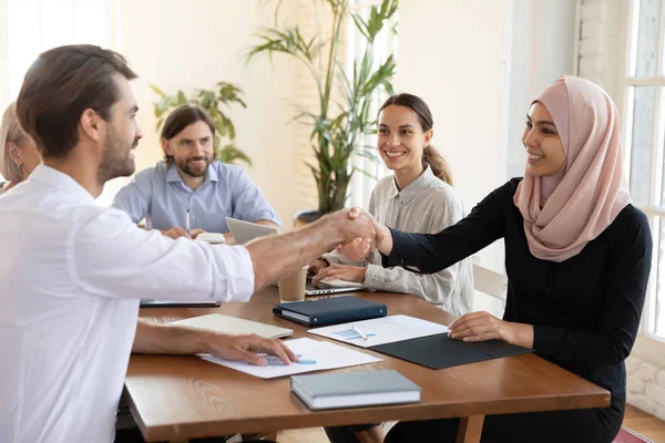 Sonriente mujer de negocios musulmana asiática estrechando la mano de su socio de negocios — Foto de Stock