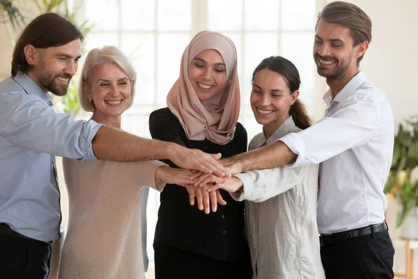 Gelukkig glimlachen diverse medewerkers hand in hand bij de vergadering — Stockfoto