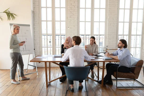 Une équipe diversifiée d'employés à l'écoute d'une femme d'affaires d'âge moyen lors d'une réunion — Photo