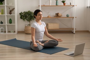 Hintli kadın evde internet dersiyle yoga yapıyor.