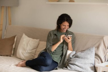 Çok mutlu bir kadın akıllı telefon kullanıyor, gülüyor, aletlerle eğleniyor.