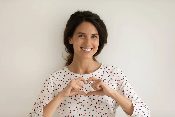 Head shot portrait smiling woman showing heart gesture on chest — Stock Photo, Image