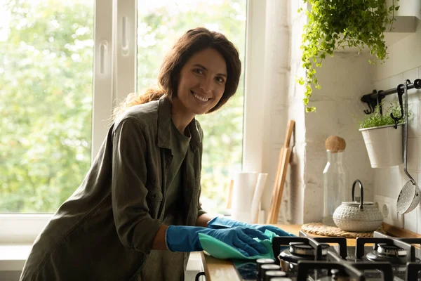 Porträt einer lächelnden Hausfrau in Handschuhen beim Küchenputzen — Stockfoto