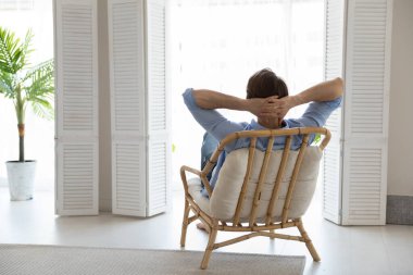 Rahat genç adam, eko bambu koltukta dinleniyor.