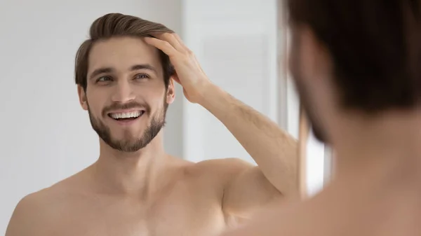 Happy handsome young guy combing smooth brown hair with fingers — Stock Photo, Image