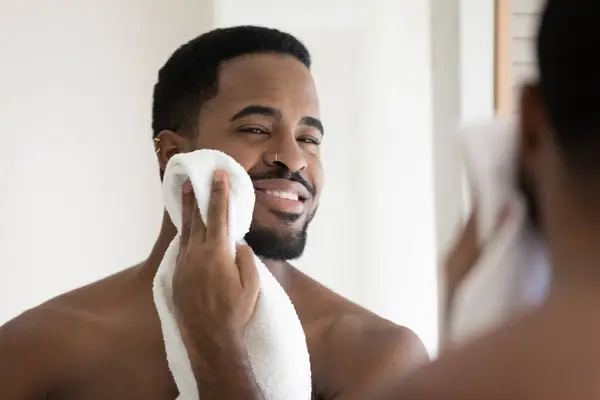 Happy handsome African American guy drying face with white towel — Stock Photo, Image