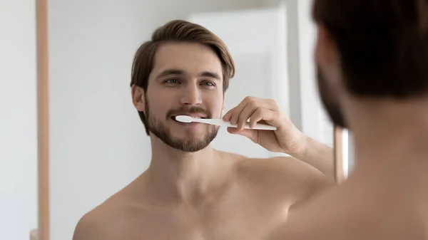 Positivo guapo bien construido chico cepillarse los dientes en el baño —  Fotos de Stock