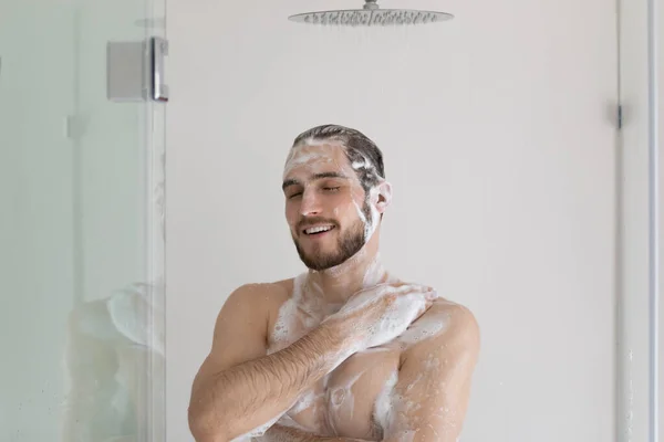 Happy relaxed handsome well built guy in soap gel foam — Stock Photo, Image