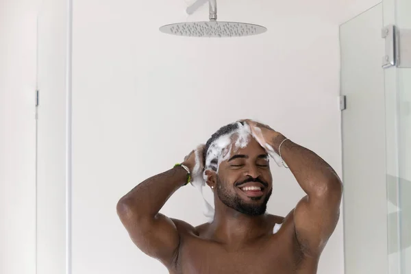 Happy athletic handsome African guy washing hair, taking shower — Stock Photo, Image