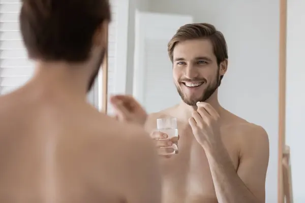 Happy handsome shirtless guy taking vitamins, food supplement — Stock Photo, Image