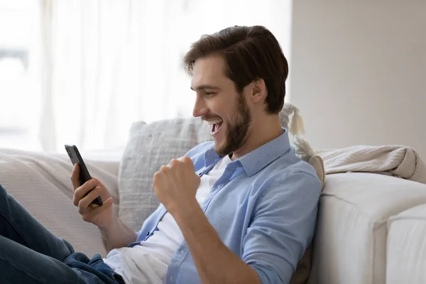 Aufgeregter glücklicher Mann nutzt Handy und bekommt überraschend gute Nachrichten — Stockfoto
