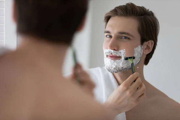 Positive attractive young guy with gel foam on lower face — Stock Photo, Image