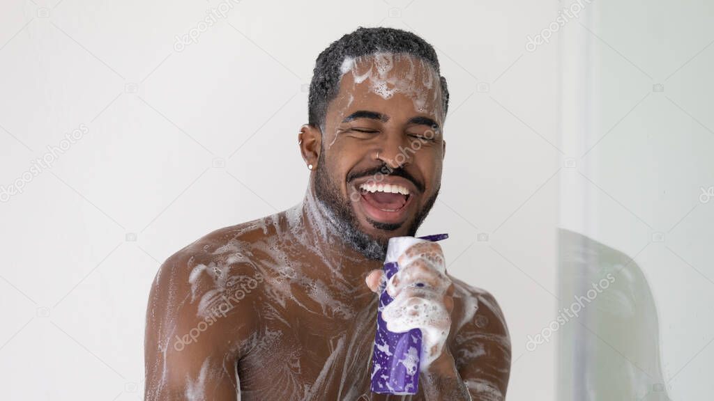 Excited African American guy taking shower, singing to music