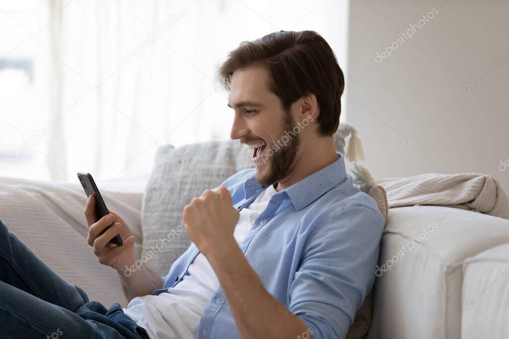 Excited happy man using mobile phone, getting surprising good news