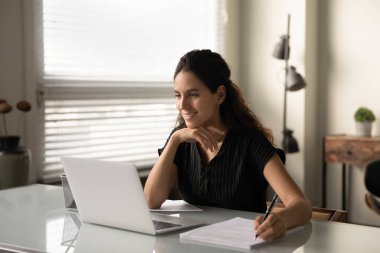 Genç beyaz kadın ofis masasında dizüstü bilgisayarda çalışıyor.