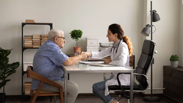 Feliz apretón de manos de la doctora vieja paciente masculino en el hospital — Foto de Stock