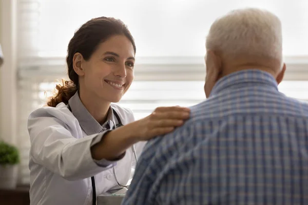 Glimlachende vrouwelijke arts ondersteuning van oude mannelijke client — Stockfoto