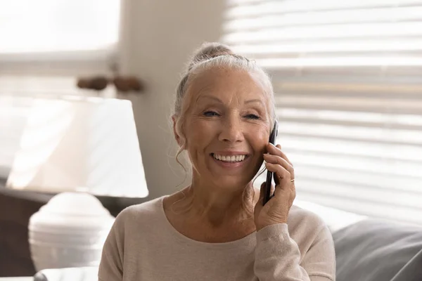Smiling mature woman talk on cellphone gadget