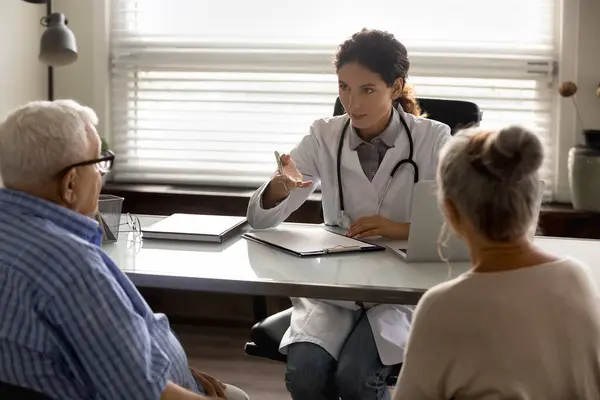 Médico femenino consulta a pacientes de pareja anciana en hospital — Foto de Stock