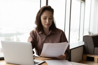 Konsantre genç iş kadını mali raporu analiz ediyor..
