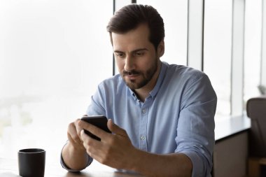 Odaklanmış genç iş adamı cep telefonu uygulamaları kapalı alanda.