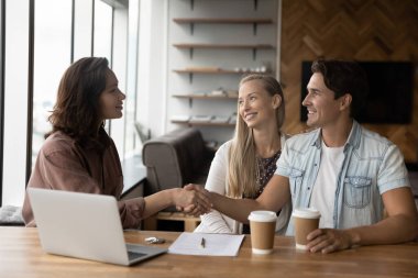 Bayan emlakçı ofiste müşterilerle tokalaşıyor..