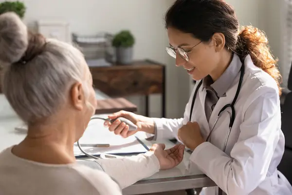 Female doctor measure blood pressure of mature patient — Stock Photo, Image