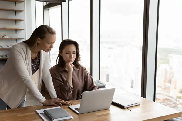 Líder feminina concentrada ajudando colega com projeto. — Fotografia de Stock