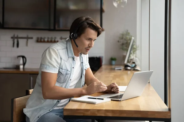 Konzentrierter junger Mann in drahtlosem Headset mit Videoanruf. — Stockfoto