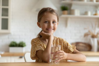 Bir bardak suyla küçük sevimli bir kızın portresi..