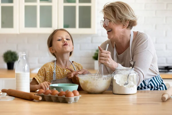 Klein meisje met plezier koken met oma in de keuken. — Stockfoto