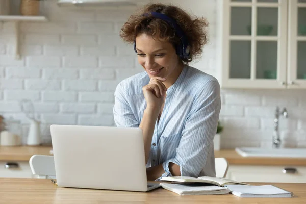 Feliz joven mujer de 30 años en los auriculares que trabajan a distancia en la computadora. —  Fotos de Stock