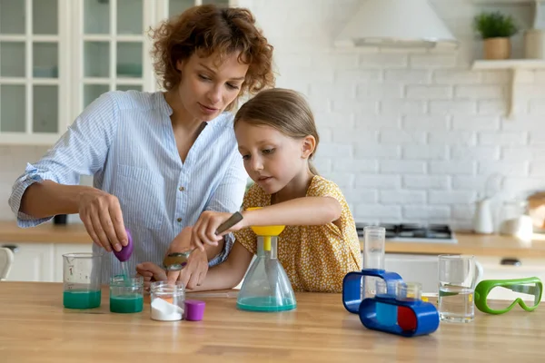 Zorgzame jonge moeder onderwijs klein meisje doen chemie experimenten. — Stockfoto