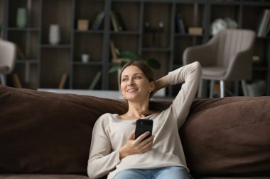 Evde akıllı telefon kullanan hayalperest bir genç kadın..