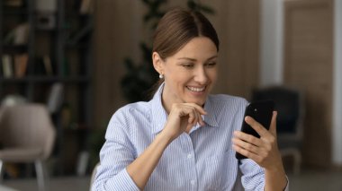 Ofisteki akıllı telefon uygulamalarını kullanan mutlu genç bir kadın..
