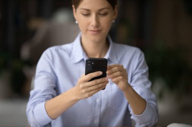 Ofiste akıllı telefon uygulaması kullanan genç bir iş kadını.