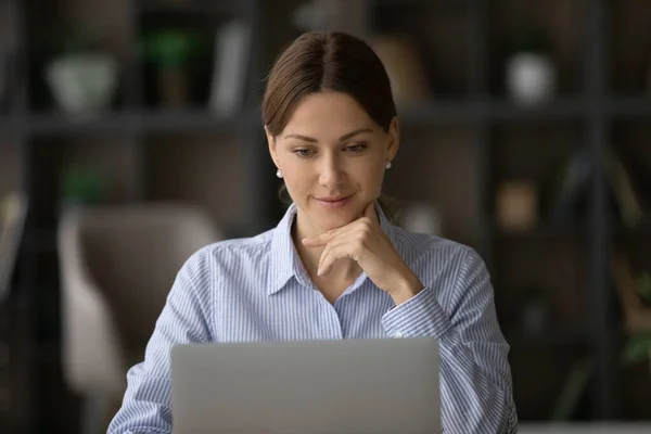 Leende eftertänksam ung affärskvinna som arbetar med dator. — Stockfoto