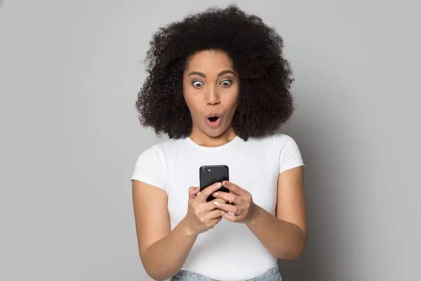 Mujer afroamericana asombrada sorprendida por noticias en el teléfono celular — Foto de Stock
