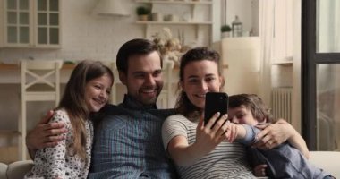 Evde akıllı telefon uygulaması kullanan dört kişilik mutlu bir aile..