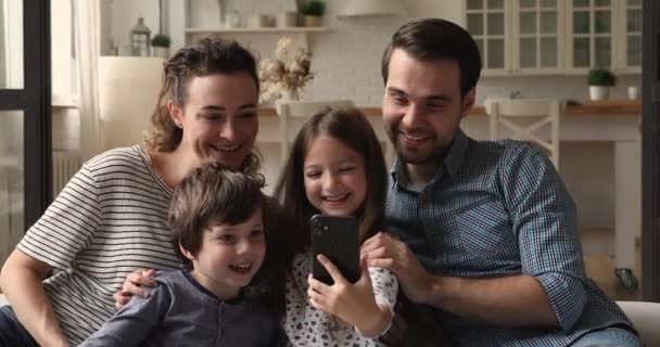 Glückliche vierköpfige Familie nutzt Handy-Anwendungen zu Hause. — Stockvideo