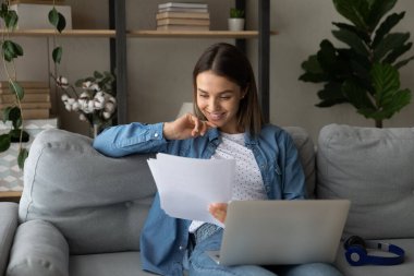 Gülümseyen, serbest çalışan, belgelerle çalışan genç bir kadın..