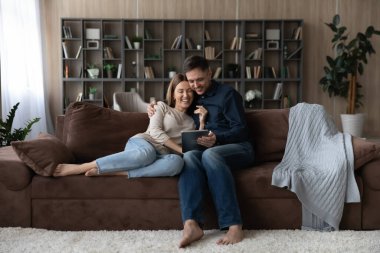 Mutlu çift evde birlikte tablet kullanarak rahatlıyor.