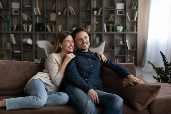 Happy couple relax on sofa look in distance — Stock fotografie